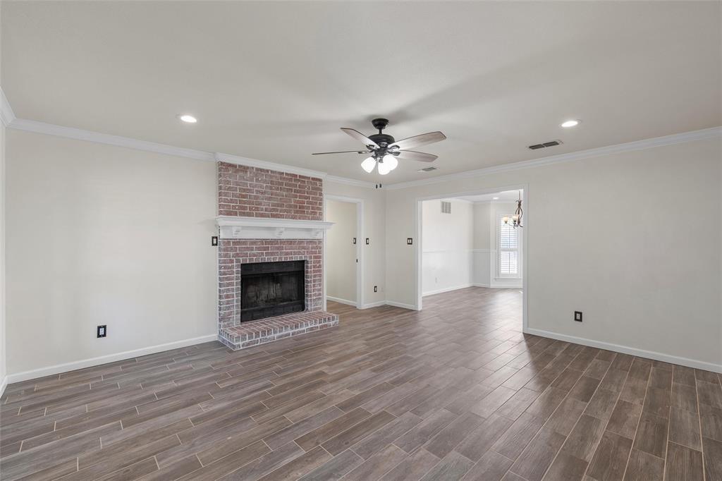 5112 Old Caufield Ranch Road McGregor, TX 76657 - Photo 11 of 38 Unfurnished living room featuring crown molding, ceiling fan, a fireplace, dark wood-style floors, and recessed lighting