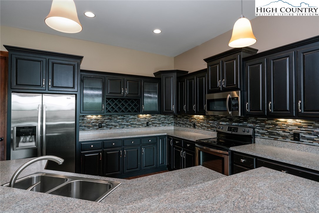 879 Winding Ridge Drive West Jefferson, NC 28694 - Photo 29 of 37 a kitchen with kitchen island granite countertop a sink stove and refrigerator