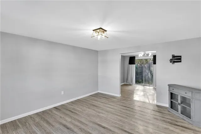 a view of an empty room with wooden floor and a fireplace