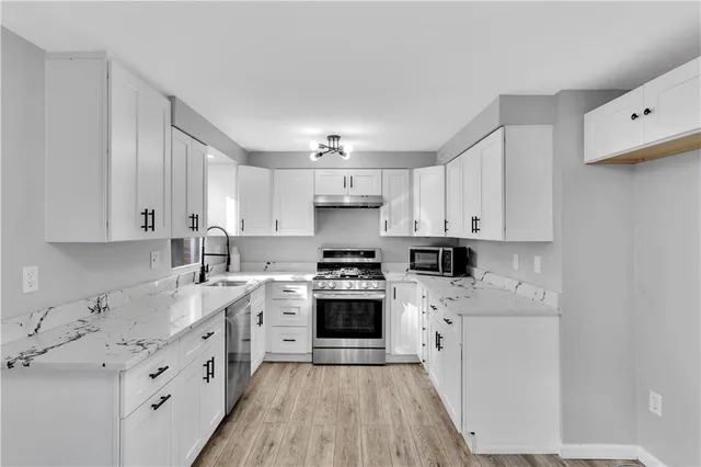 a kitchen with cabinets stainless steel appliances a sink and wooden floor