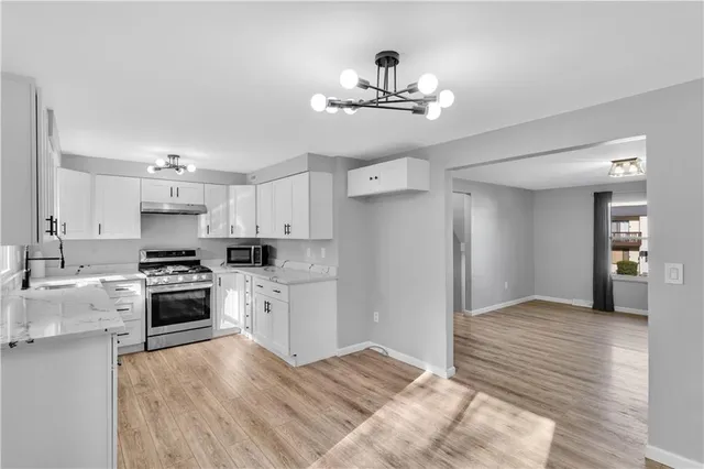 a kitchen with kitchen island white cabinets and stainless steel appliances
