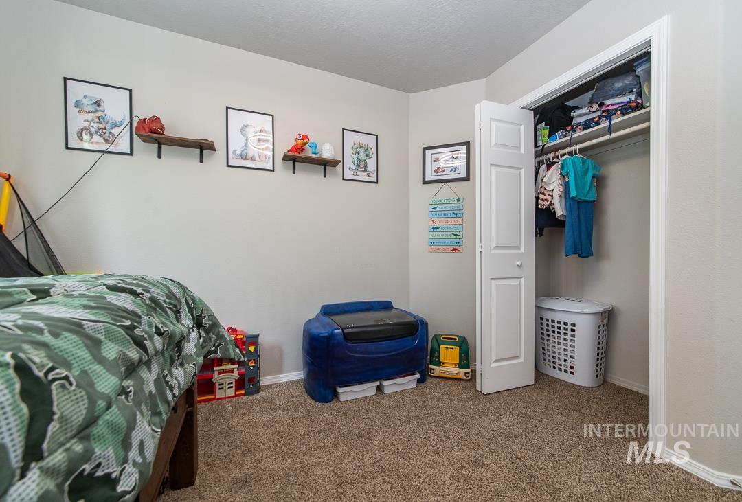 805 Bison Way Caldwell, ID 83607 - Photo 31 of 45 Carpeted room with a bi-fold closet, light neutral wall paint, and two wall-mounted wood shelves