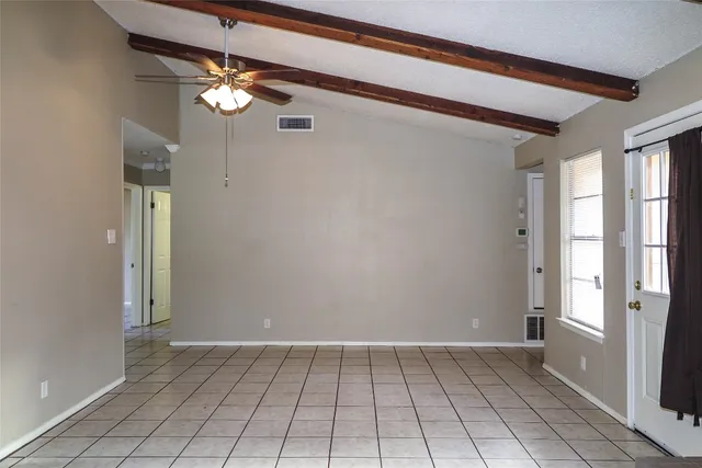 a view of an empty room with window and chandelier fan