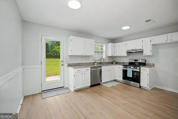 a kitchen with granite countertop a sink stove and refrigerator