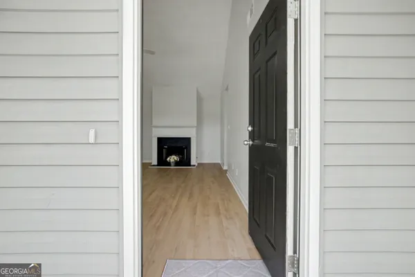 a view of an empty room with wooden floor fireplace and a window