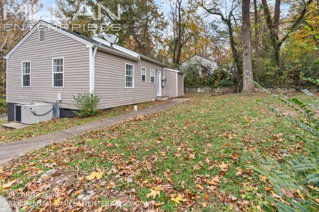 a backyard of a house with plants and large tree