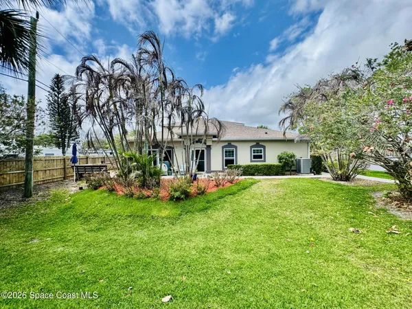a front view of a house with garden and tree