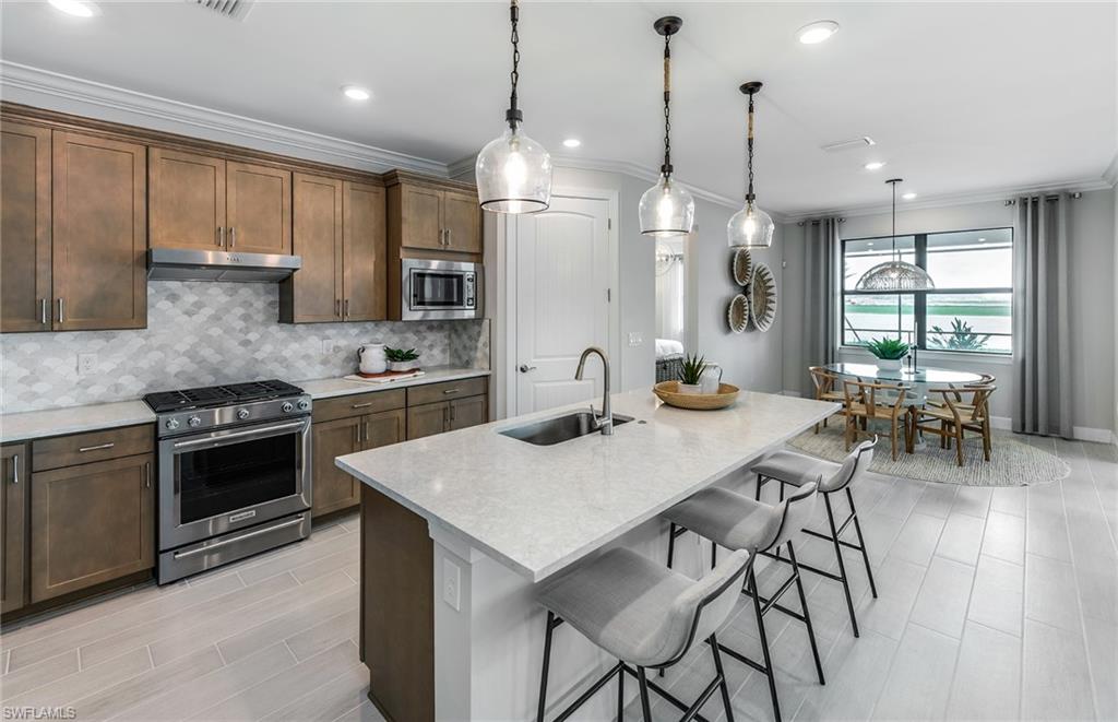 20322 Napa Loop Estero, FL 33928 - Photo 6 of 46 a kitchen with stainless steel appliances kitchen island granite countertop a stove a refrigerator a sink a dining table and chairs with wooden floor