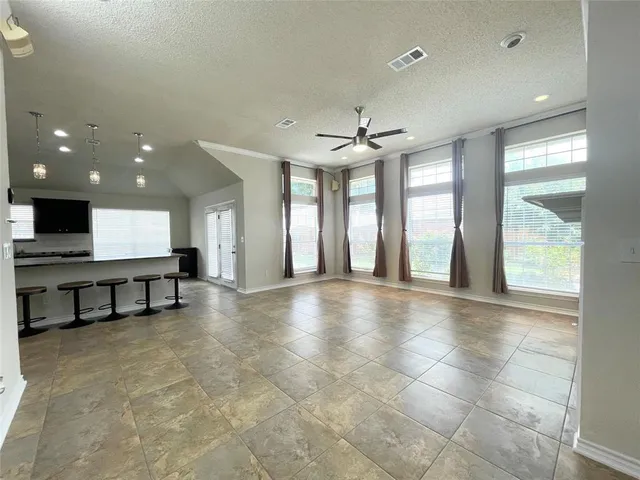 a view of an empty room with kitchen and window