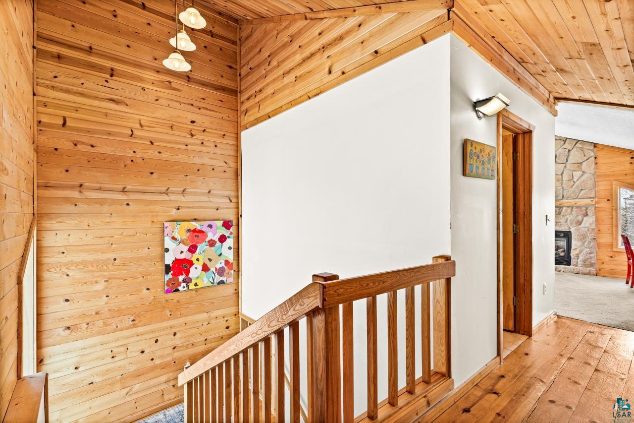 67 Snowshoe Trail Tofte, MN 55615 - Photo 30 of 42 Hallway featuring an upstairs landing, a vaulted wooden ceiling, wooden walls, and hardwood / wood-style floors