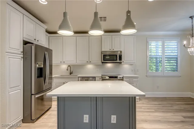 a kitchen with stainless steel appliances a stove a refrigerator a sink and white cabinets