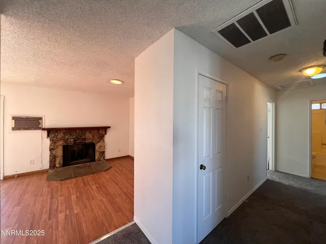 an empty room with wooden floor fireplace and windows