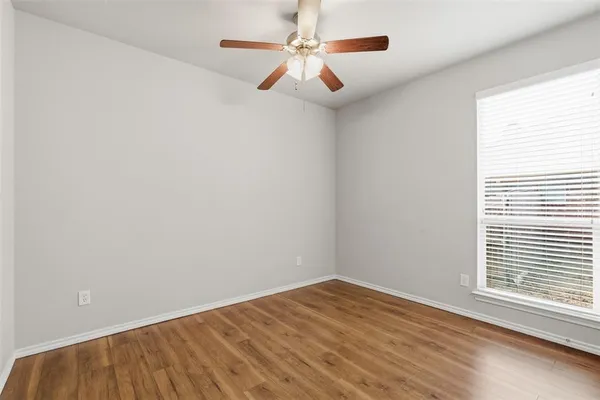 an empty room with a window and a ceiling fan