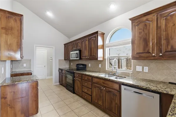a kitchen with stainless steel appliances granite countertop a stove a sink and a microwave