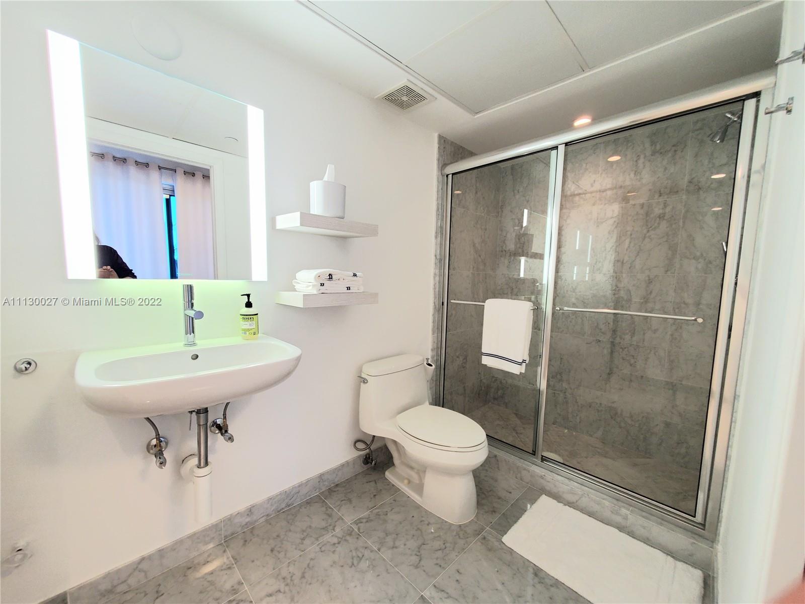 9401 Collins Avenue, Unit 607 Surfside, FL 33154 - Photo 44 of 58 a bathroom with a sink toilet a mirror and shower