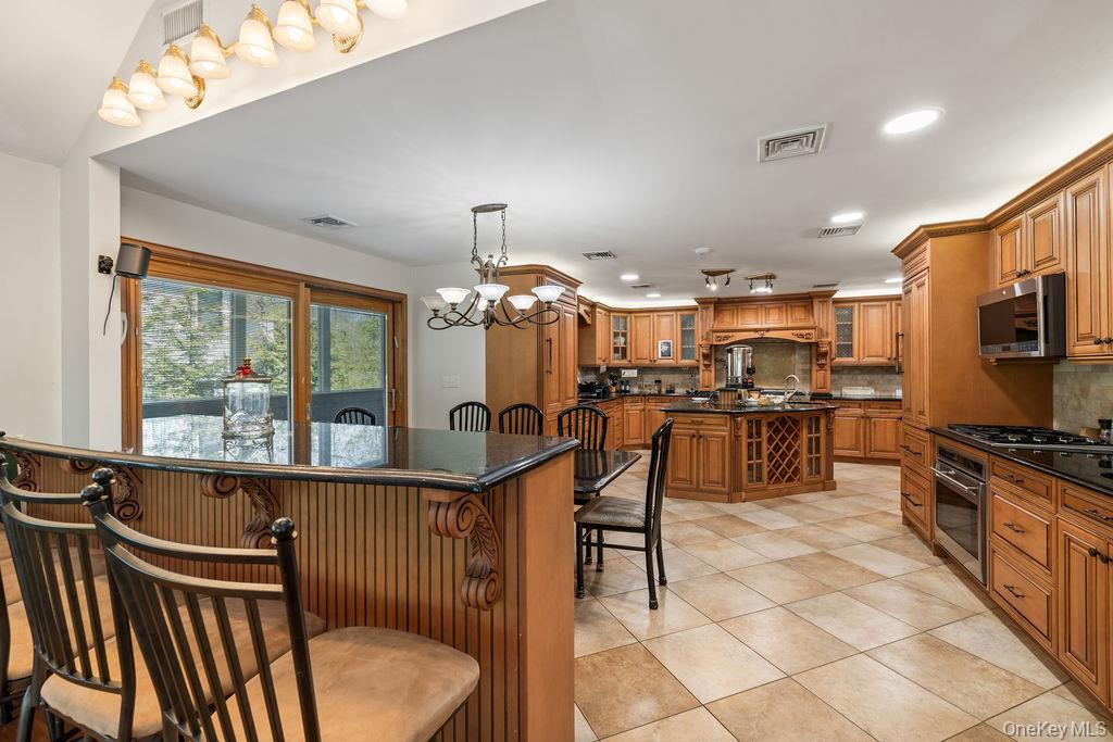 10 Elyise Road Monsey, NY 10952 - Photo 15 of 40 a kitchen with stainless steel appliances kitchen island granite countertop a stove a sink a dining table and chairs with wooden floor