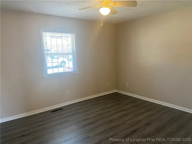 an empty room with wooden floor and a ceiling fan