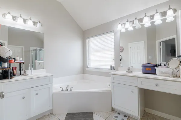 a bathroom with a tub a sink double vanity and mirror