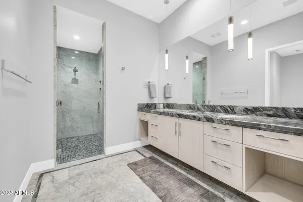a bathroom with a granite countertop sink two mirror and shower