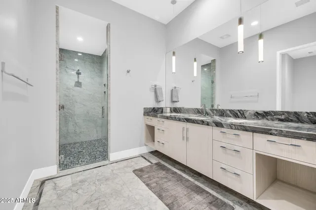 a bathroom with a granite countertop sink two mirror and shower