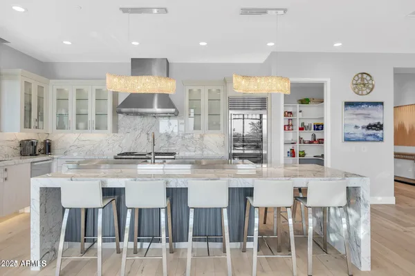 a kitchen with stainless steel appliances granite countertop a dining table chairs and a refrigerator