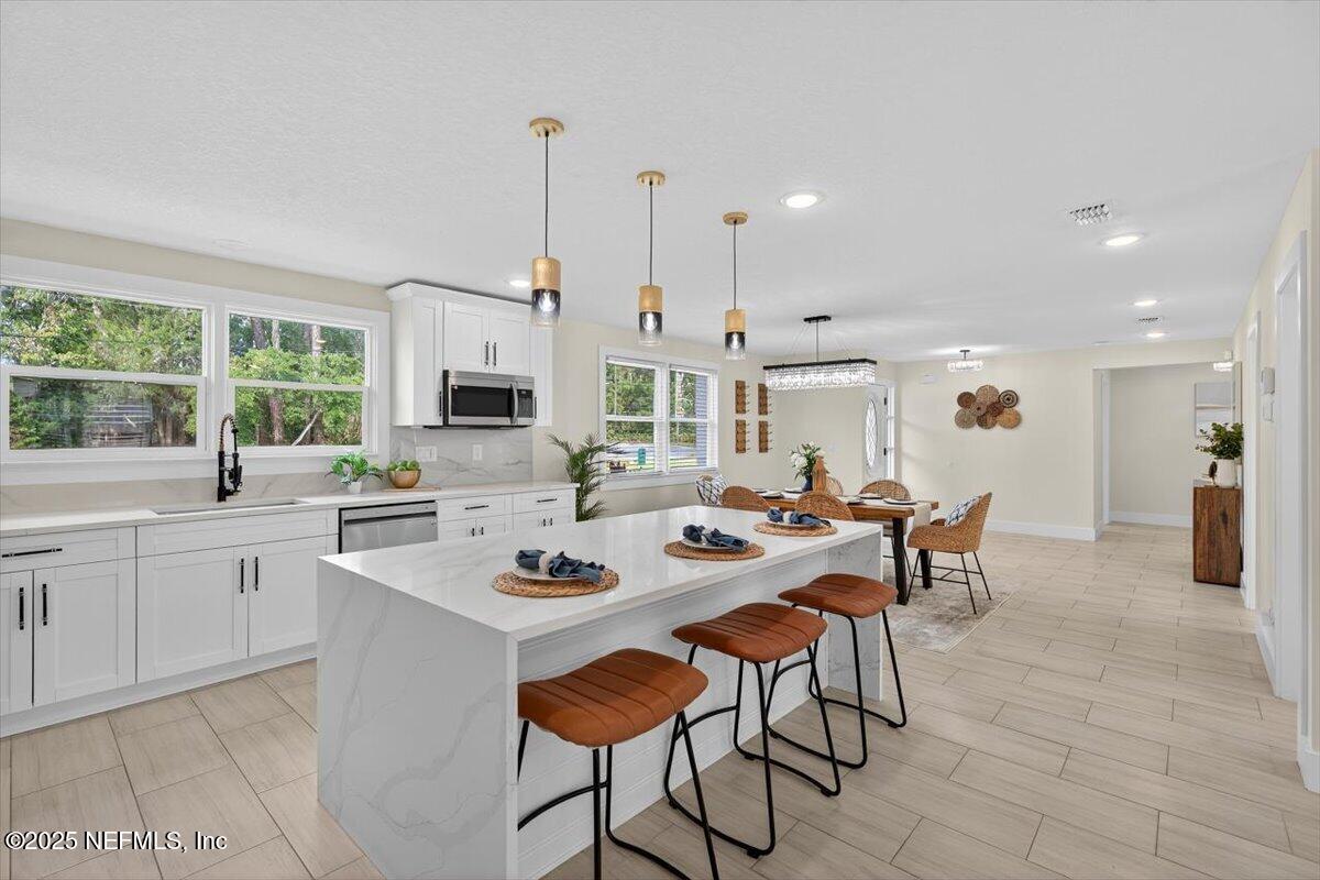 10779 Scott Mill Road Jacksonville, FL 32223 - Photo 16 of 82 a kitchen with stainless steel appliances kitchen island granite countertop a stove a sink a dining table and chairs with wooden floor