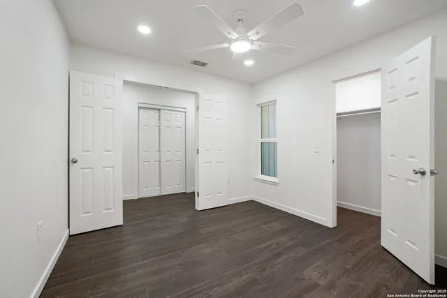 an empty room with wooden floor and ceiling fan