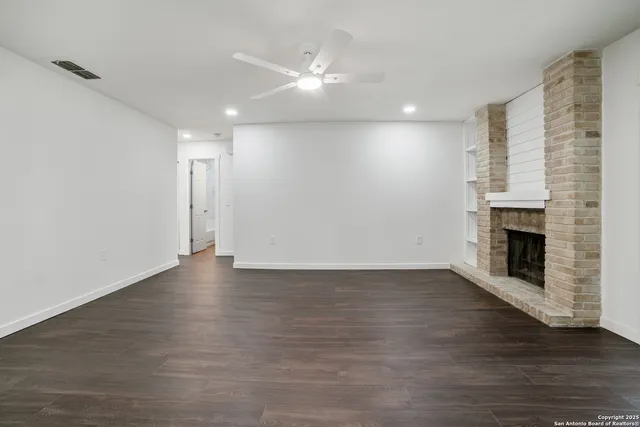 a view of empty room with wooden floor and fireplace