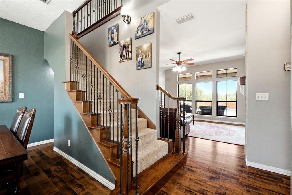 600 Aspen Street Pilot Point, TX 76258 - Photo 22 of 39 Interior staircase with a dark wood handrail, wrought iron balusters, and carpeted treads