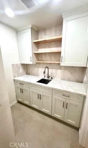 a utility room with granite countertop cabinets and sink