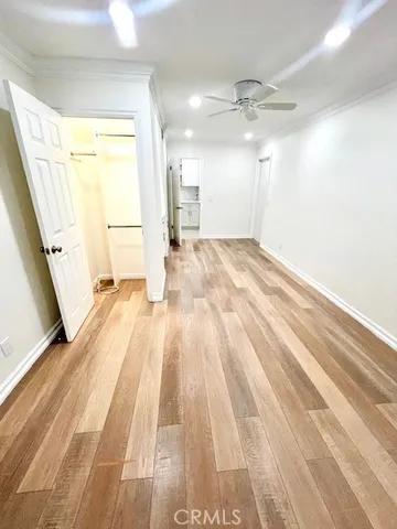 a view of empty room with wooden floor and fan