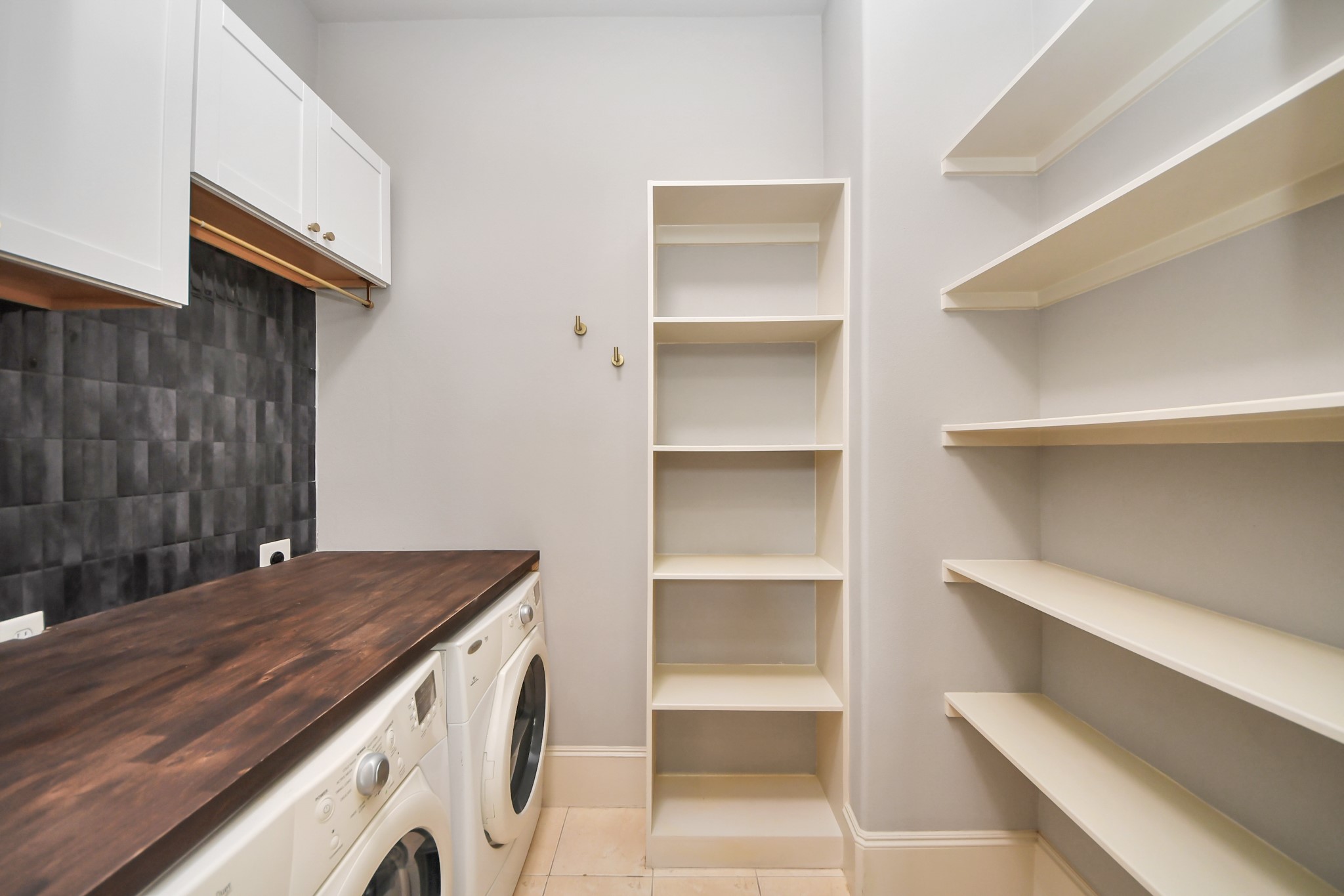 3229 Maxroy Street Houston, TX 77008 - Photo 29 of 43 A functional laundry room and pantry combo featuring washer and dryer station, a dark wood counter for folding, and extensive shelving for maximum storage space.