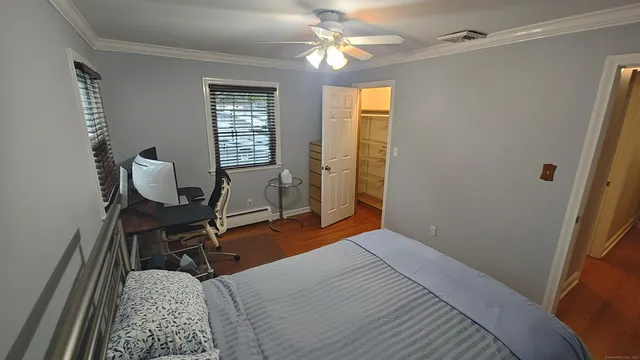 a bedroom with a bed windows and chair