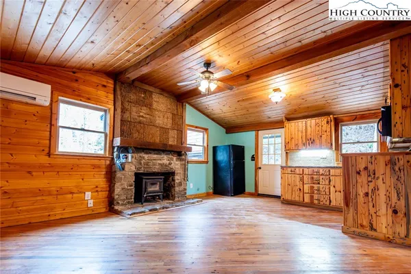 a view of an empty room with wooden floor fireplace and a window
