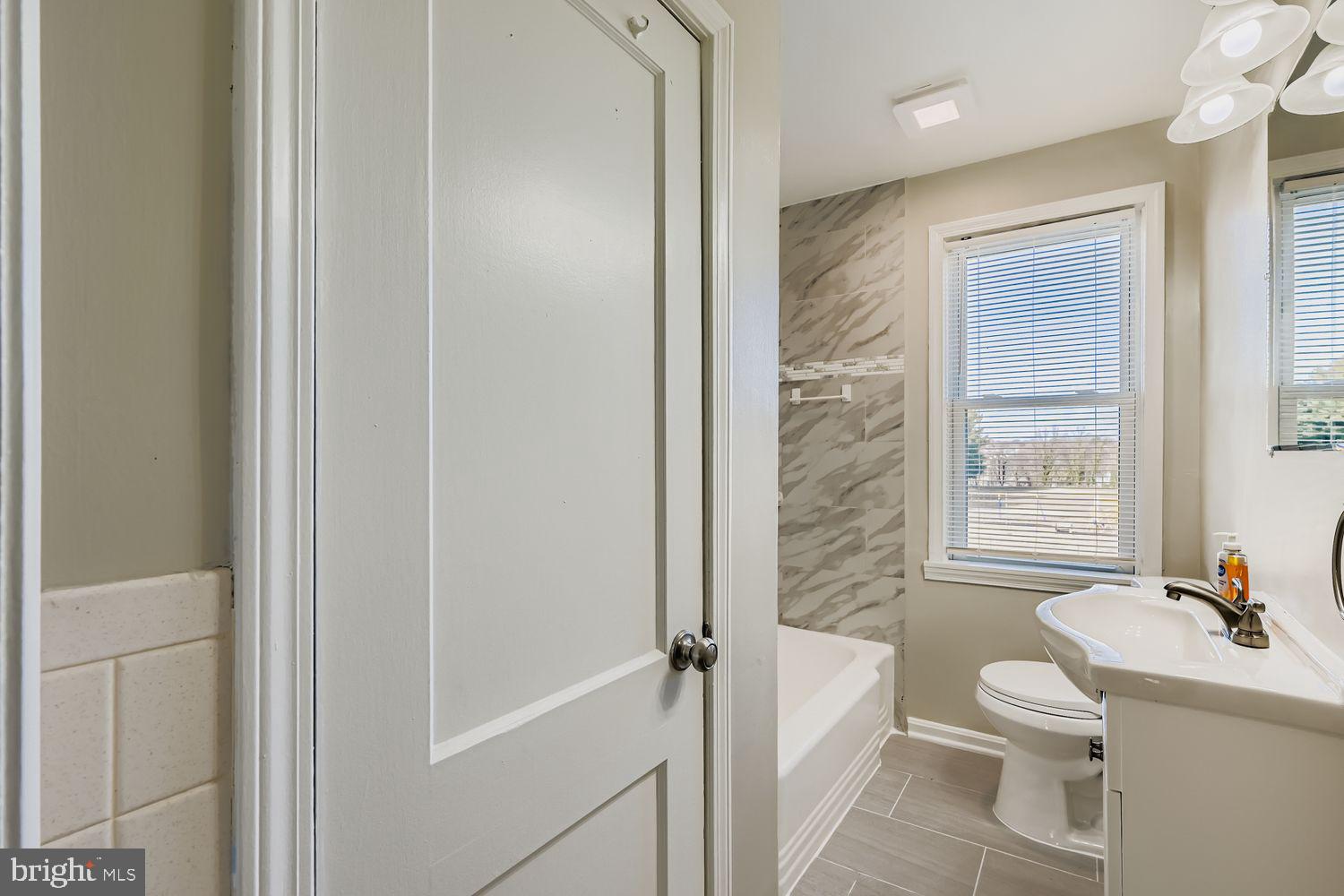 3711 Ina Avenue Baltimore, MD 21206 - Photo 15 of 29 a bathroom with a granite countertop sink toilet a mirror and shower