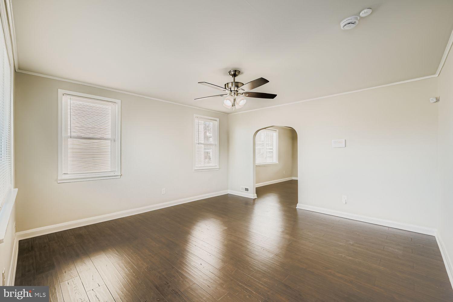 3711 Ina Avenue Baltimore, MD 21206 - Photo 5 of 29 an empty room with wooden floor chandelier fan and windows