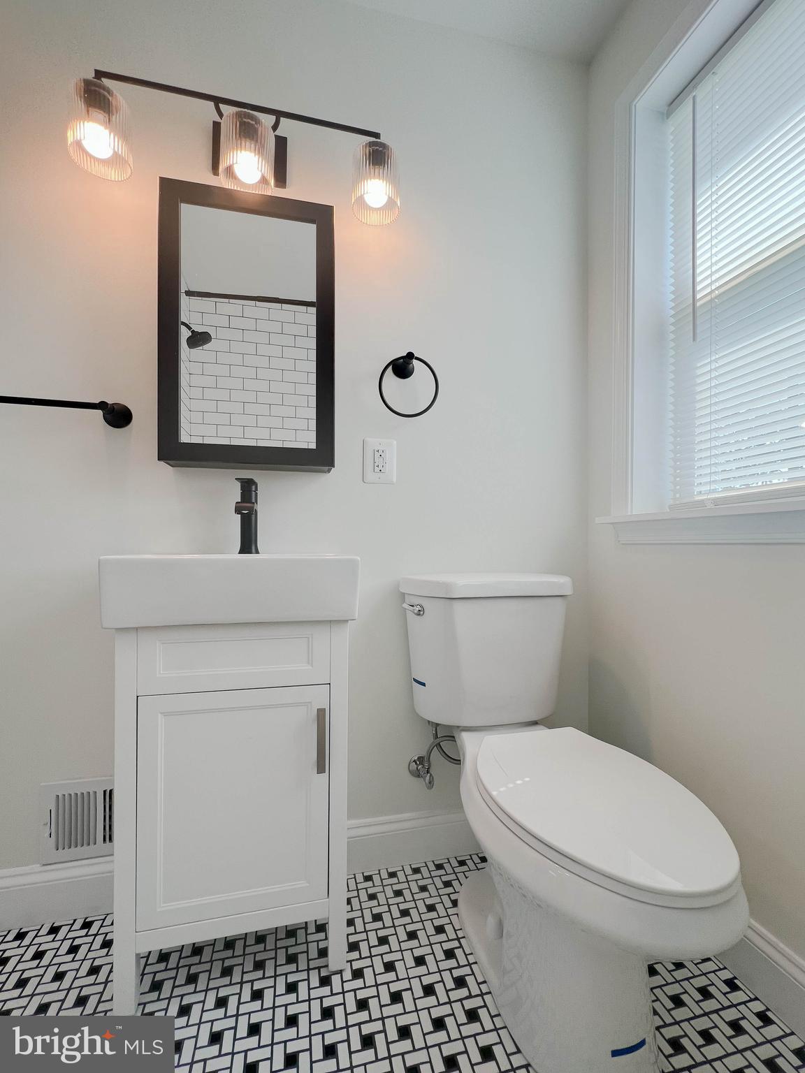 5564 Channing Road Baltimore, MD 21229 - Photo 21 of 32 a bathroom with a toilet sink vanity and mirror