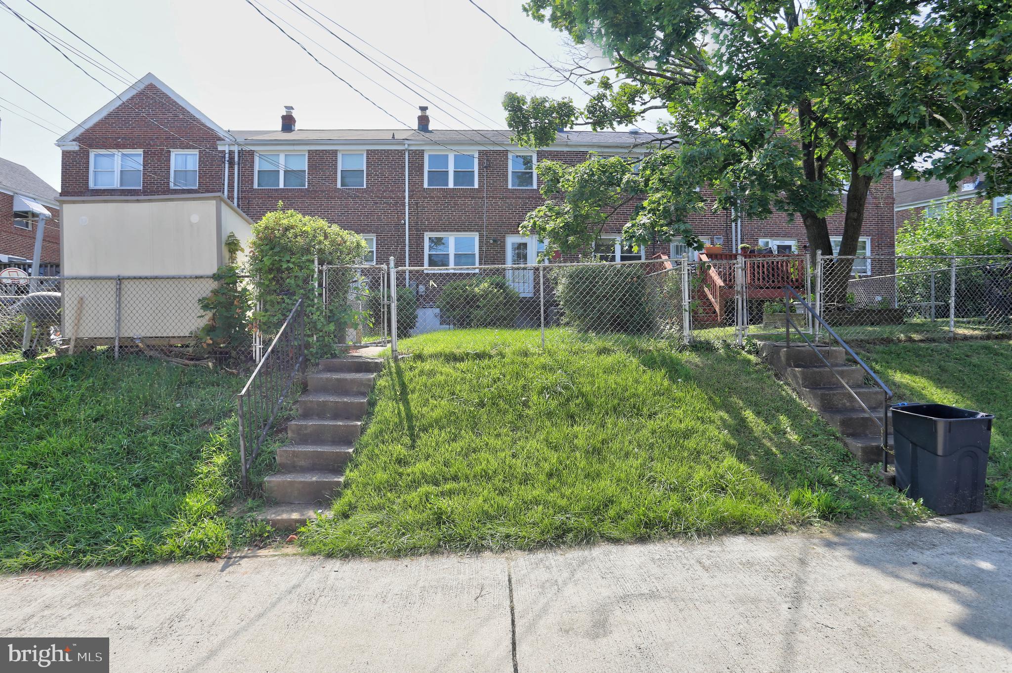 5564 Channing Road Baltimore, MD 21229 - Photo 29 of 32 a view of a brick house with a yard plants and large tree