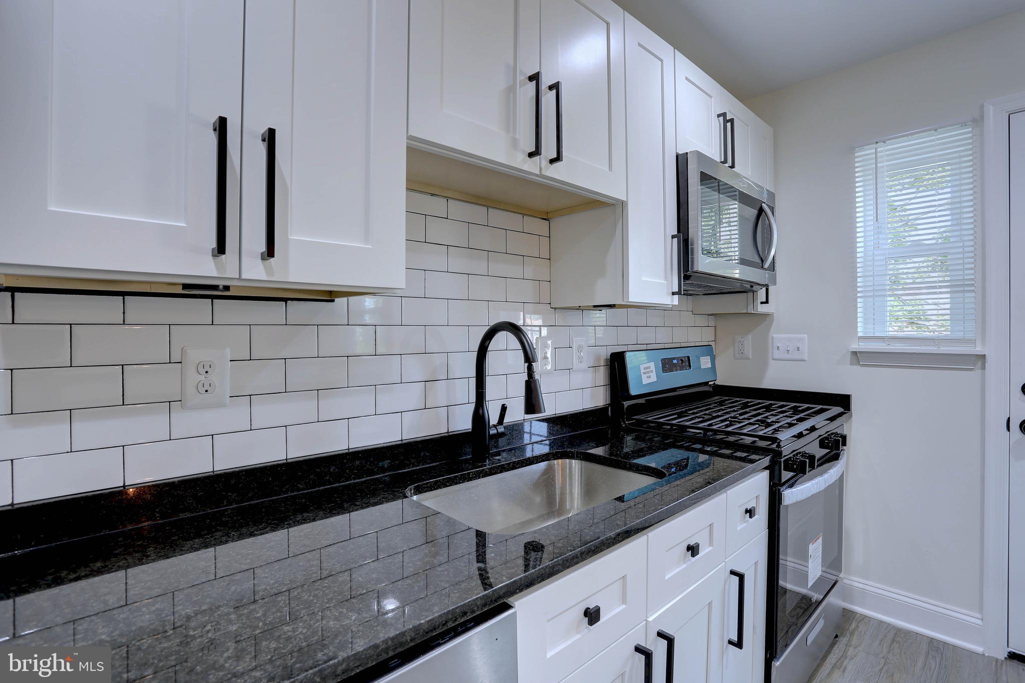 5564 Channing Road Baltimore, MD 21229 - Photo 3 of 32 a kitchen with granite countertop a sink a stove and cabinets