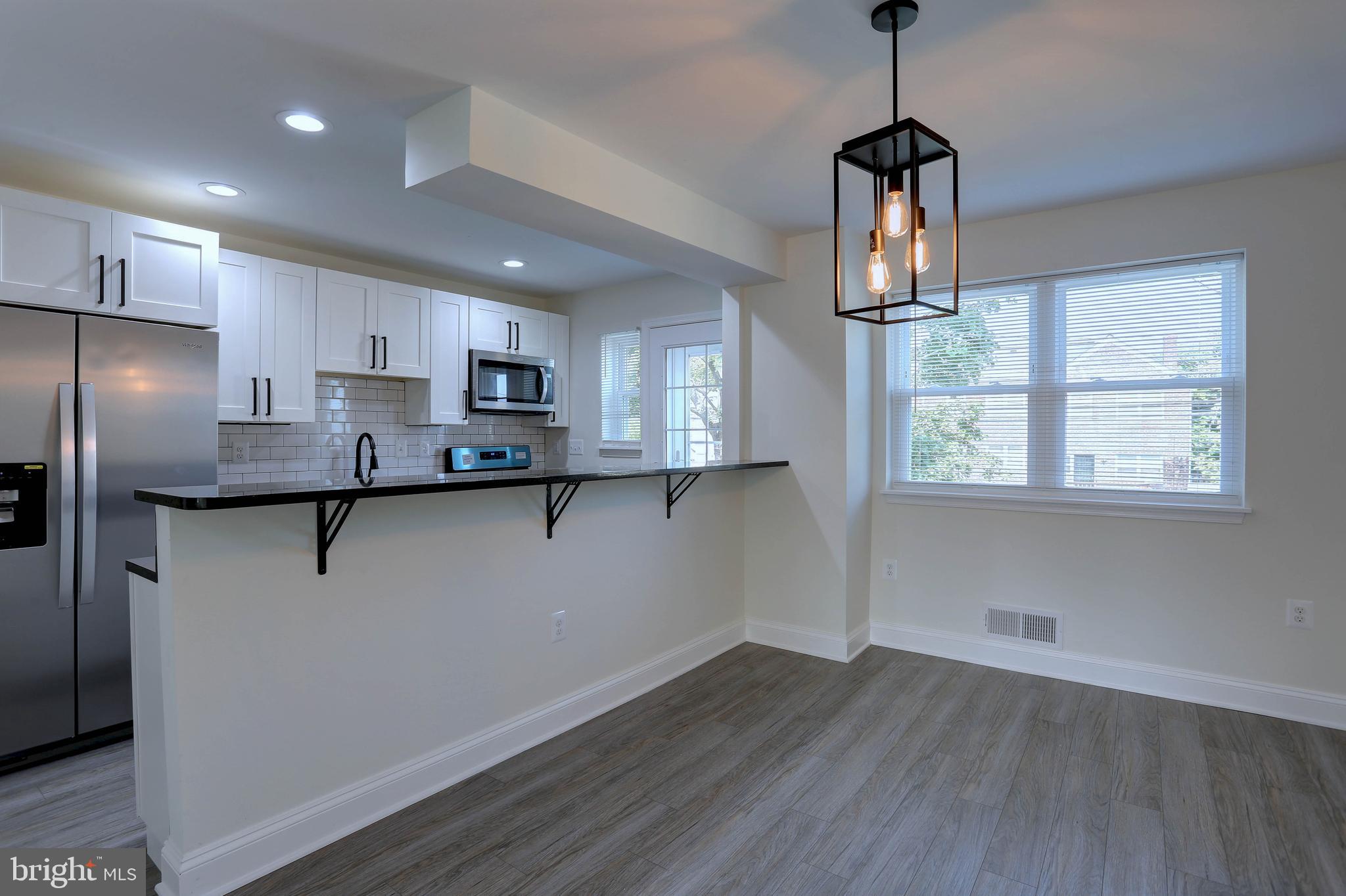 5564 Channing Road Baltimore, MD 21229 - Photo 8 of 32 a kitchen with stainless steel appliances granite countertop a refrigerator a sink dishwasher a stove and white cabinets with wooden floor