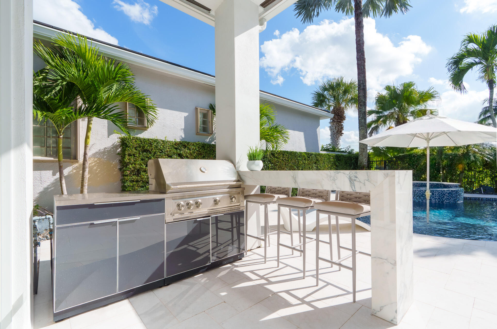 7952 Trieste Place Delray Beach, FL 33446 - Photo 42 of 59 a view of a patio with a dining table and chairs under an umbrella with a fire pit