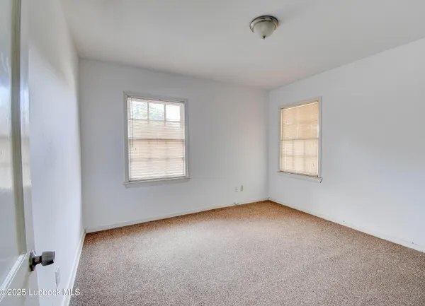 an empty room with chandelier fan and windows