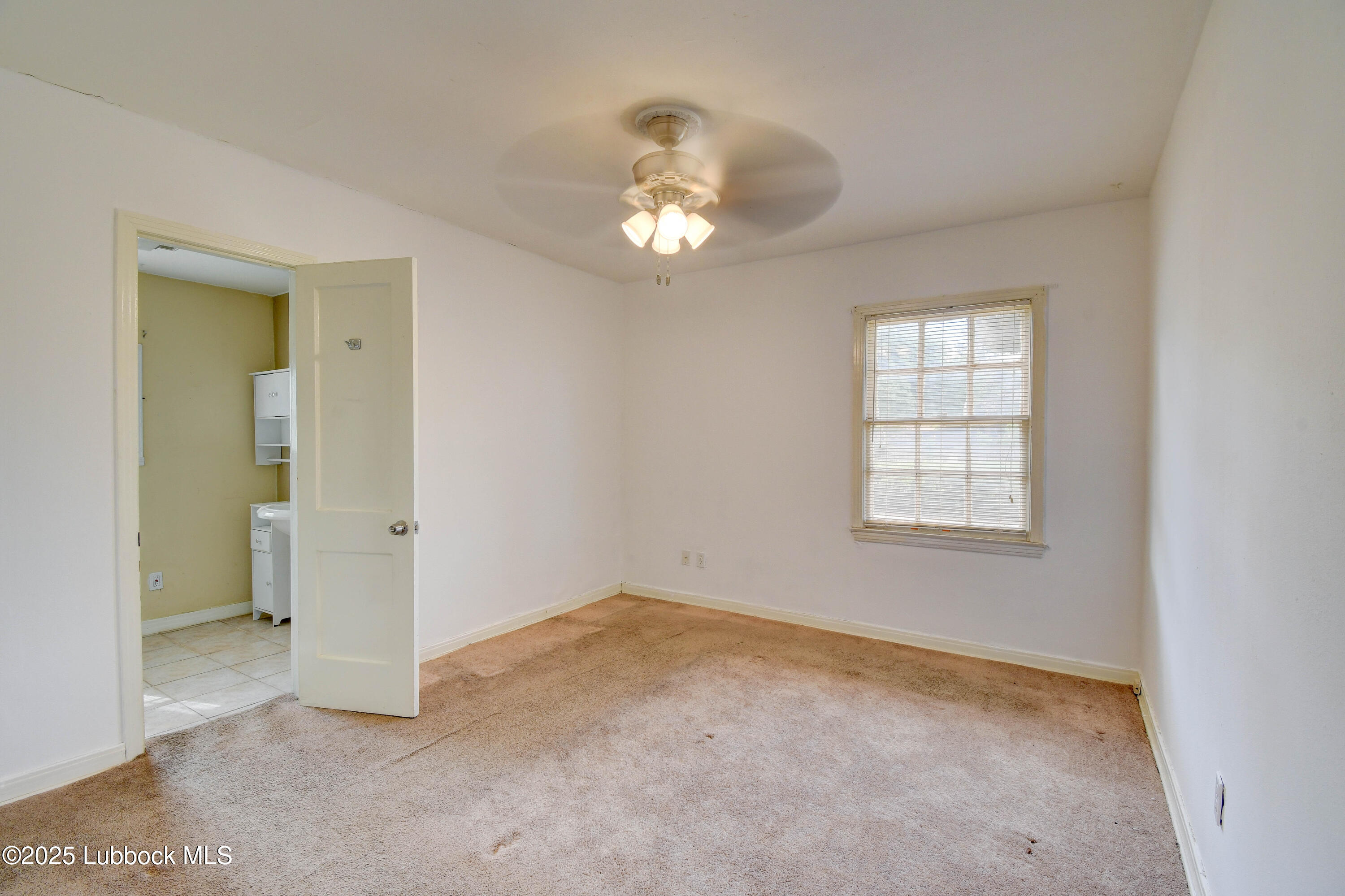 1130 West Garza Street Slaton, TX 79364 - Photo 12 of 16 an empty room with chandelier fan and windows