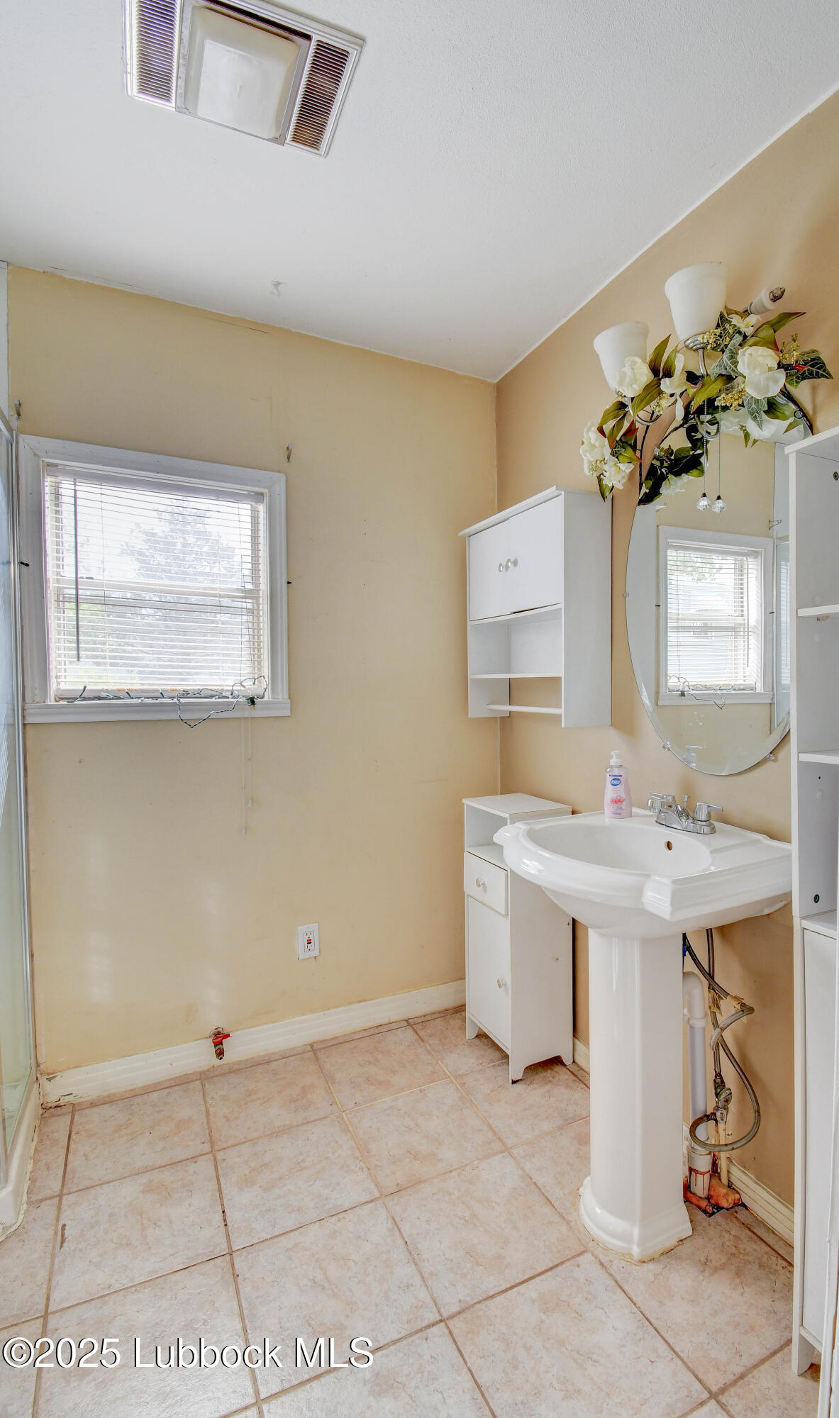 1130 West Garza Street Slaton, TX 79364 - Photo 14 of 16 a view of a bathroom with a sink a mirror and a shower