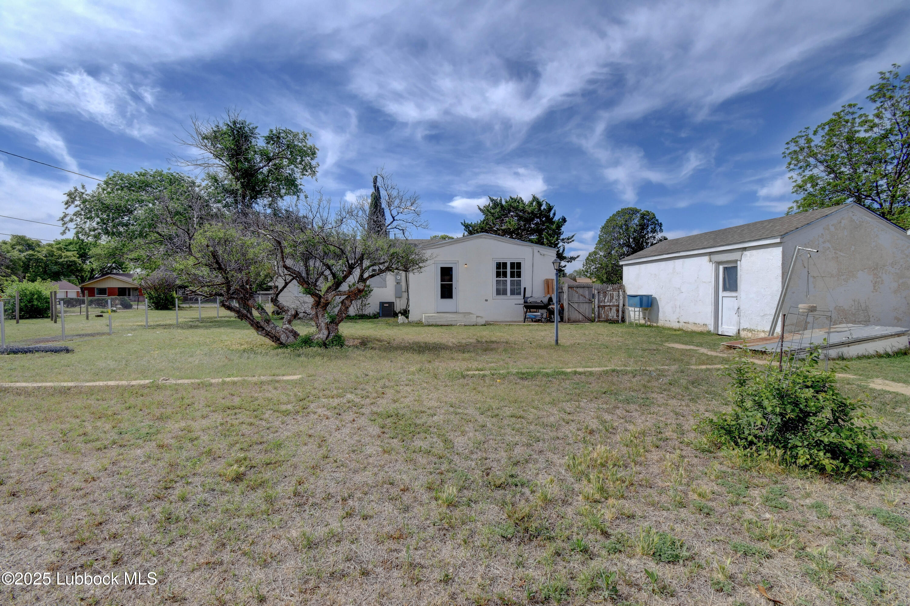 1130 West Garza Street Slaton, TX 79364 - Photo 15 of 16 a view of a white house with a big yard and large trees