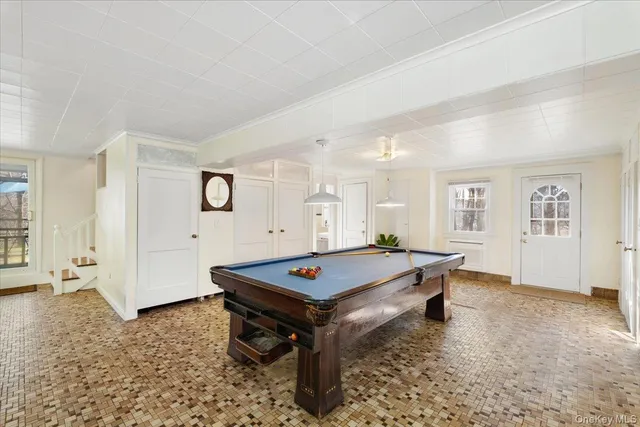 a living room with furniture pool table and wooden floor