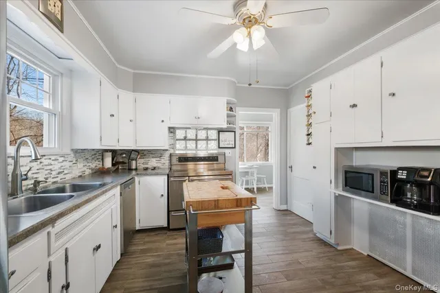 a kitchen with stainless steel appliances a stove a sink dishwasher a refrigerator and white cabinets with wooden floor