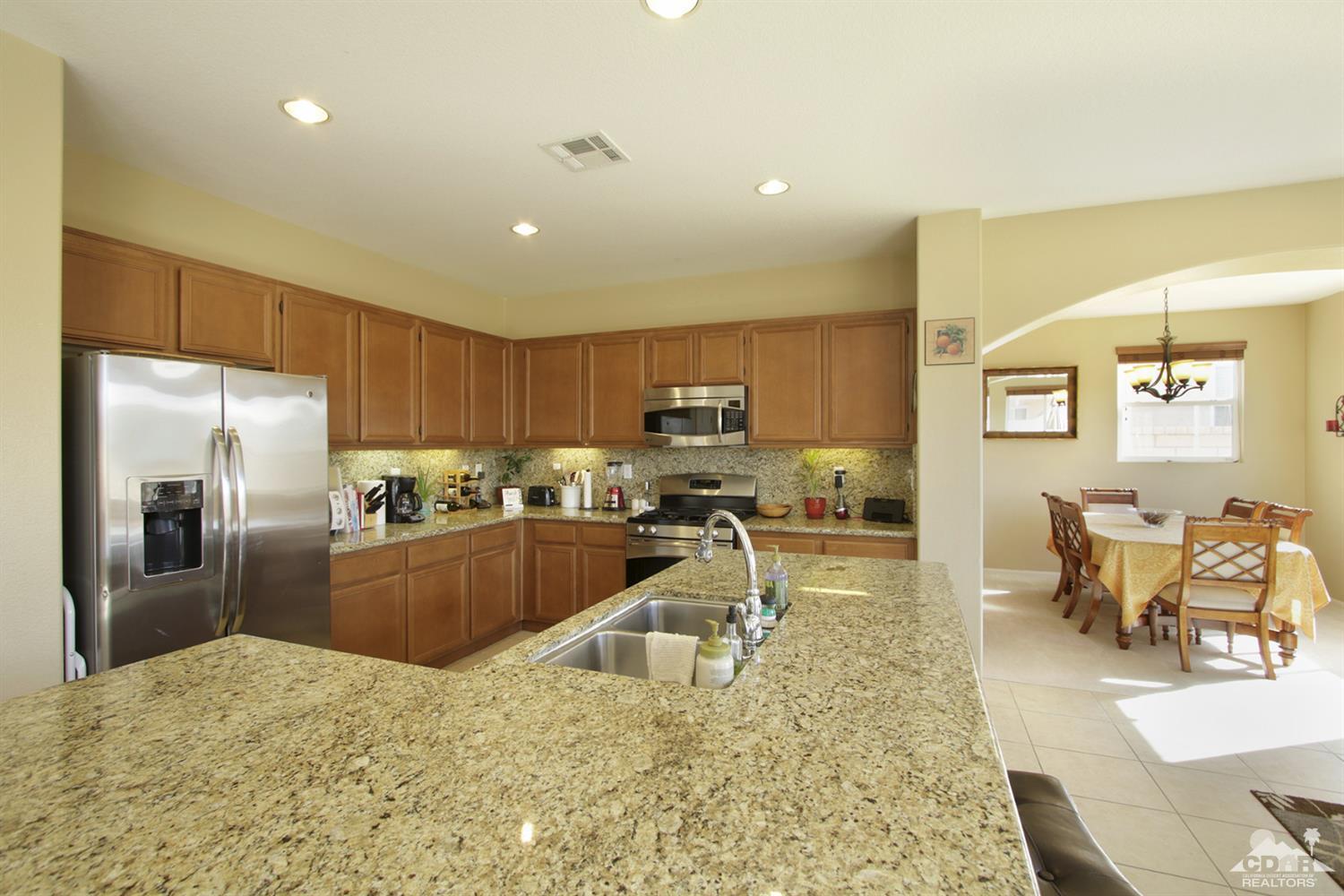 82785 Mount Riley Drive Indio, CA 92203 - Photo 6 of 35 a kitchen with a refrigerator a sink a counter top space and living room view