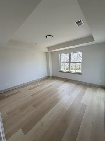 a view of an empty room with a window and wooden floor