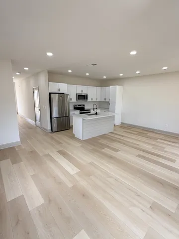 a view of kitchen with kitchen island granite countertop stainless steel appliances refrigerator sink and cabinets